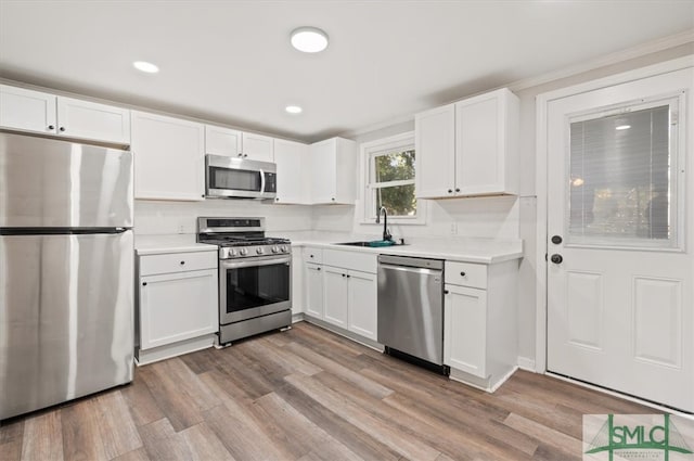 kitchen with light hardwood / wood-style floors, sink, white cabinetry, and stainless steel appliances