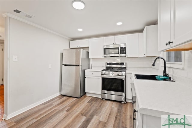 kitchen with sink, white cabinets, stainless steel appliances, and light hardwood / wood-style floors