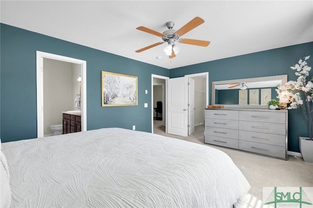 bedroom featuring a closet, light carpet, a walk in closet, ensuite bath, and ceiling fan