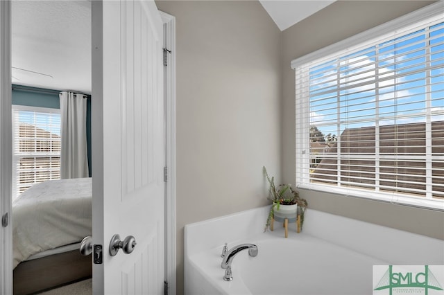 bathroom with lofted ceiling, a textured ceiling, and a washtub