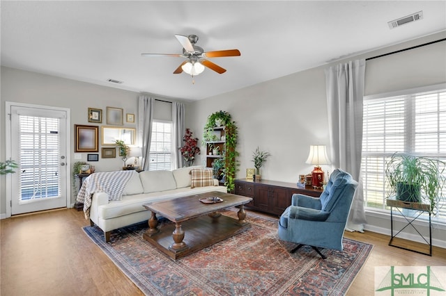 living room with light hardwood / wood-style flooring, ceiling fan, and plenty of natural light