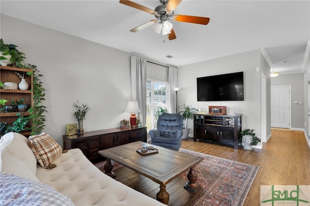 living room with ornamental molding, light hardwood / wood-style floors, and ceiling fan