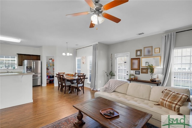 living room featuring light hardwood / wood-style floors, plenty of natural light, and ceiling fan with notable chandelier