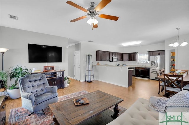 living room featuring ceiling fan with notable chandelier and light wood-type flooring