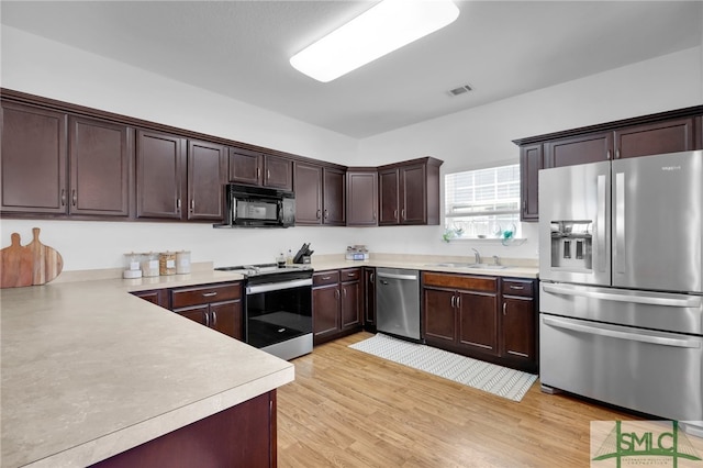 kitchen with sink, stainless steel appliances, dark brown cabinets, and light hardwood / wood-style flooring