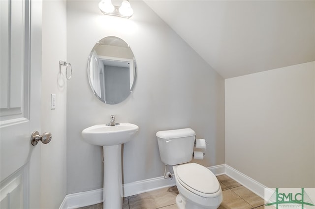 bathroom featuring toilet, sink, tile patterned floors, and vaulted ceiling