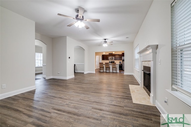 unfurnished living room featuring ceiling fan, a tile fireplace, and dark hardwood / wood-style flooring