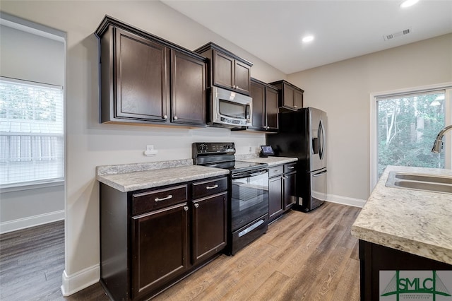 kitchen with light hardwood / wood-style floors, appliances with stainless steel finishes, sink, and plenty of natural light