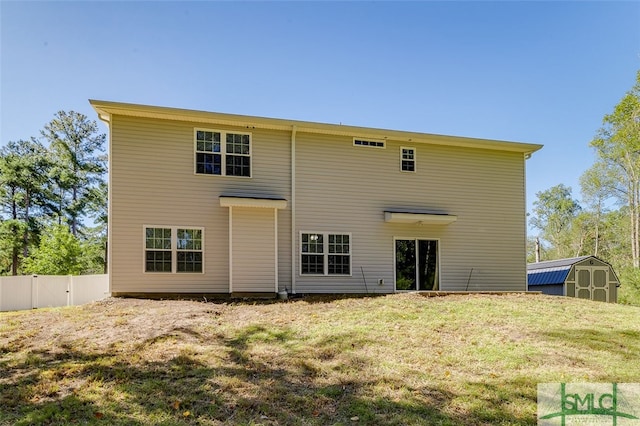 back of property with a storage unit and a yard