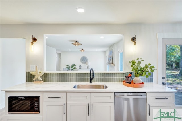 kitchen featuring stainless steel dishwasher, sink, white cabinets, and backsplash