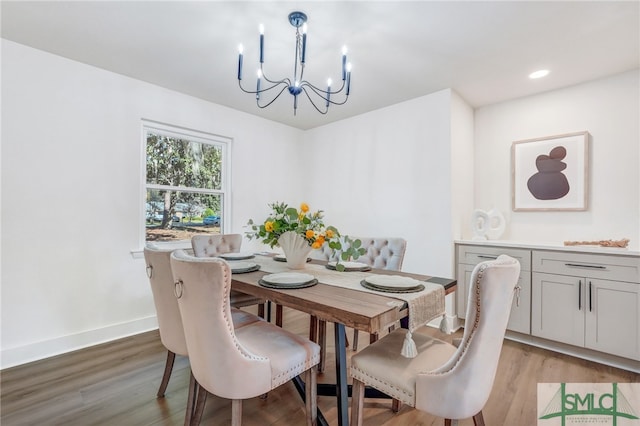 dining space with light hardwood / wood-style floors and an inviting chandelier