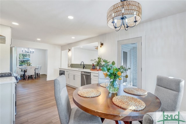 dining area featuring a chandelier, sink, wine cooler, and light wood-type flooring