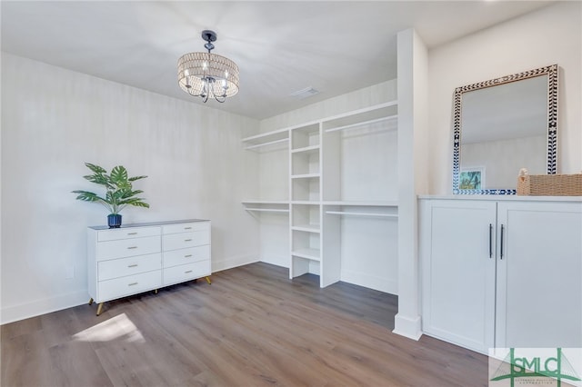 walk in closet featuring dark wood-type flooring and a chandelier