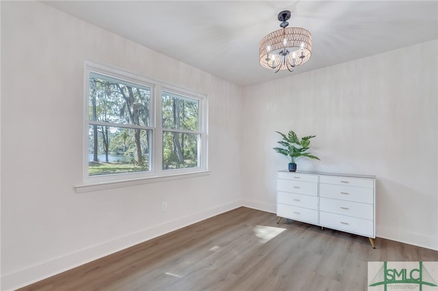 empty room featuring an inviting chandelier and wood-type flooring