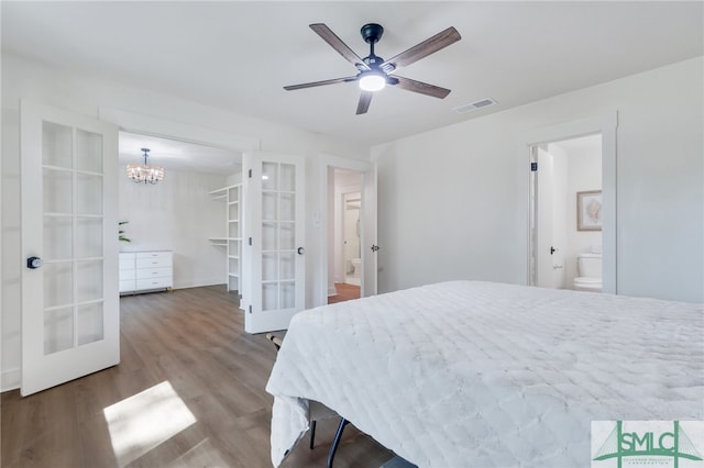 bedroom featuring connected bathroom, hardwood / wood-style flooring, french doors, and ceiling fan with notable chandelier