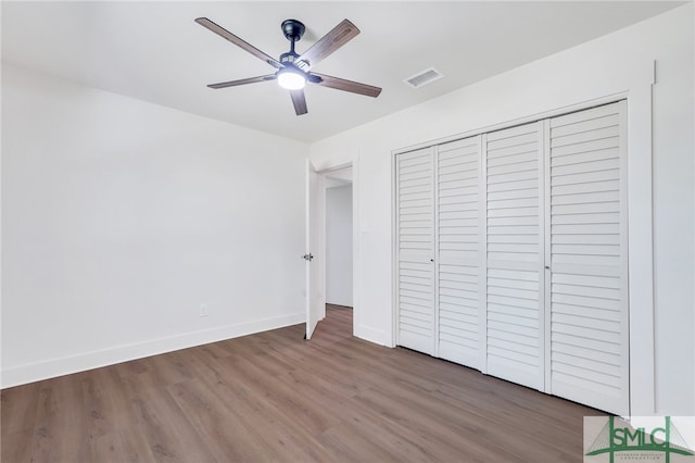 unfurnished bedroom featuring wood-type flooring, a closet, and ceiling fan