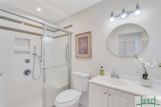 bathroom featuring a shower with door, vanity, and toilet