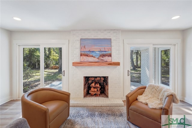 living area with a brick fireplace and light wood-type flooring