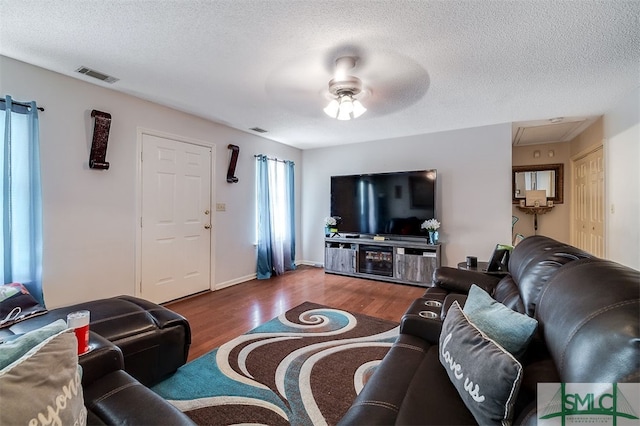 living room with ceiling fan, a textured ceiling, and dark hardwood / wood-style flooring