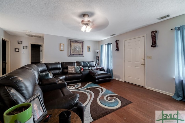 living room with ceiling fan, a textured ceiling, and dark hardwood / wood-style floors