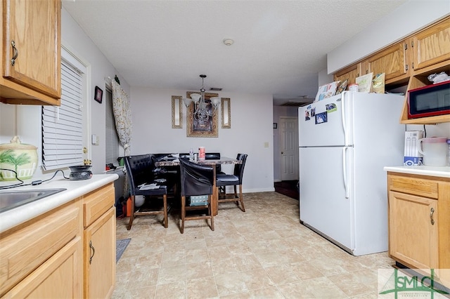 kitchen featuring white fridge and light brown cabinetry