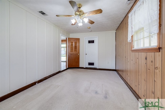 empty room with ceiling fan, a healthy amount of sunlight, a textured ceiling, and light carpet