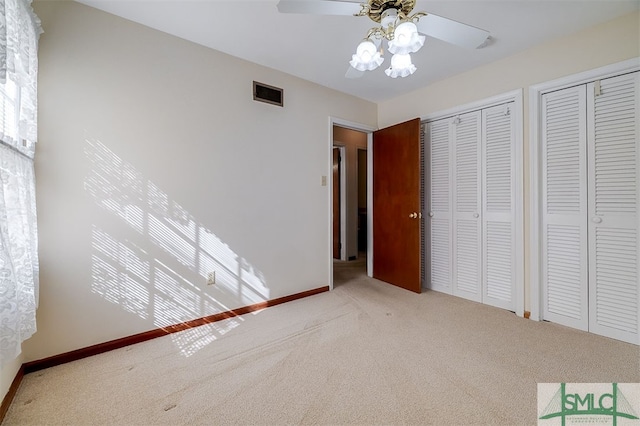 unfurnished bedroom featuring multiple closets, carpet flooring, and ceiling fan