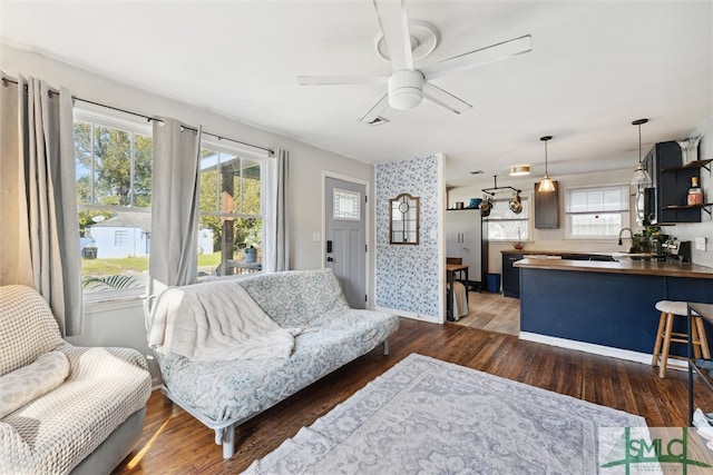 living room featuring dark wood-type flooring, a healthy amount of sunlight, and ceiling fan