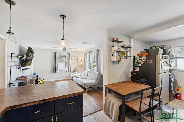 interior space with washer / dryer, stainless steel fridge, light hardwood / wood-style floors, and wood counters