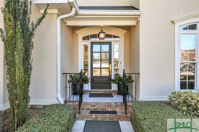 property entrance featuring a shingled roof and stucco siding