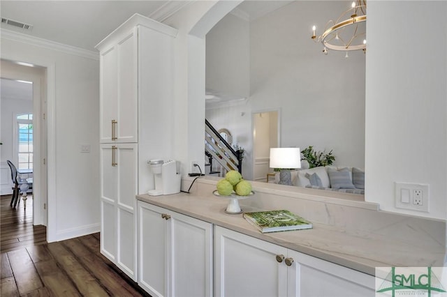 interior space with arched walkways, dark wood-style flooring, crown molding, light countertops, and white cabinets