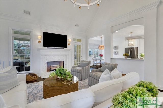 living room with arched walkways, high vaulted ceiling, a fireplace, visible vents, and an inviting chandelier