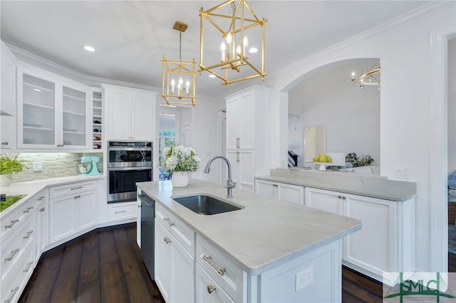 kitchen with appliances with stainless steel finishes, a sink, a kitchen island with sink, and white cabinetry