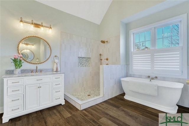 full bathroom with vaulted ceiling, tiled shower, wood finished floors, and vanity