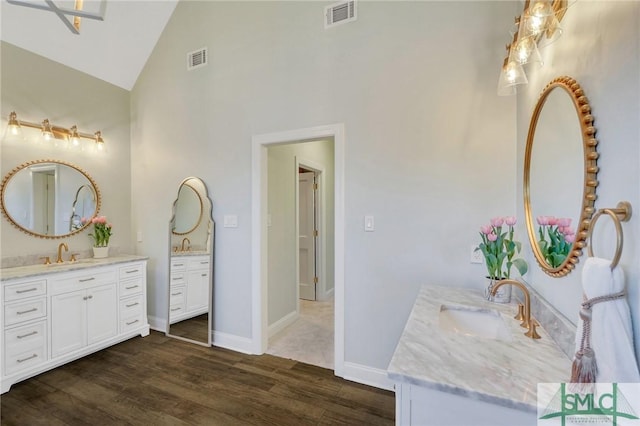 full bathroom with visible vents, two vanities, a sink, and wood finished floors