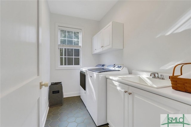 clothes washing area featuring dark tile patterned floors, a sink, baseboards, cabinet space, and washer and clothes dryer