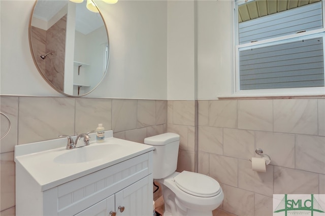 bathroom with toilet, vanity, and tile walls