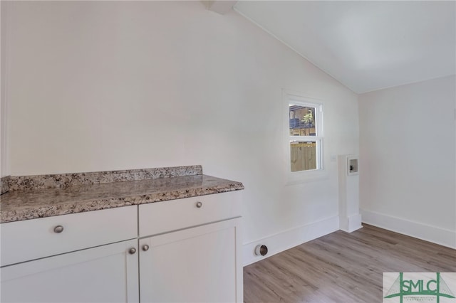 washroom featuring washer hookup, light hardwood / wood-style floors, and cabinets