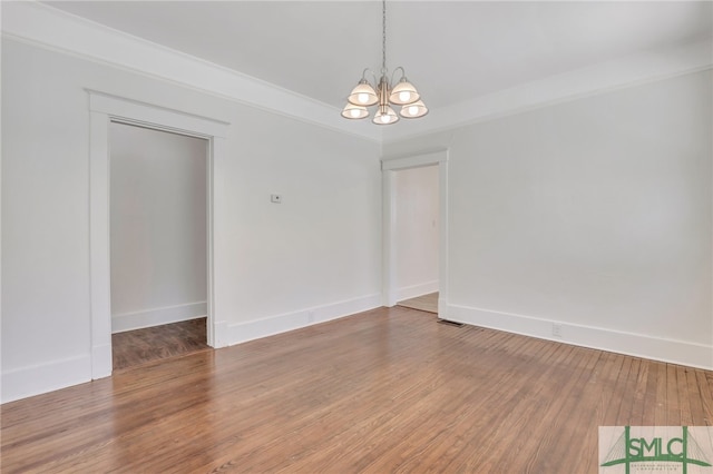 spare room featuring a notable chandelier and wood-type flooring