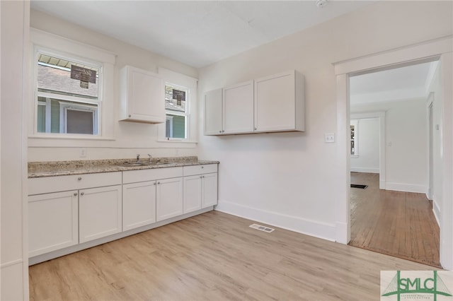 kitchen with light hardwood / wood-style flooring, white cabinets, a healthy amount of sunlight, and sink