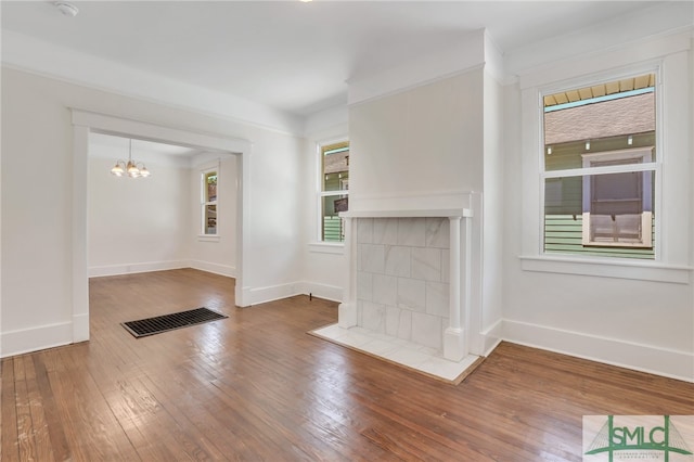 unfurnished living room featuring a notable chandelier, hardwood / wood-style flooring, and a fireplace