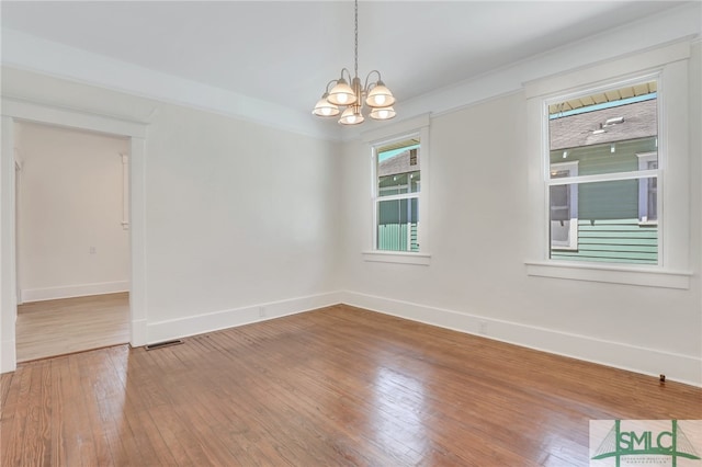 spare room with hardwood / wood-style floors and a chandelier