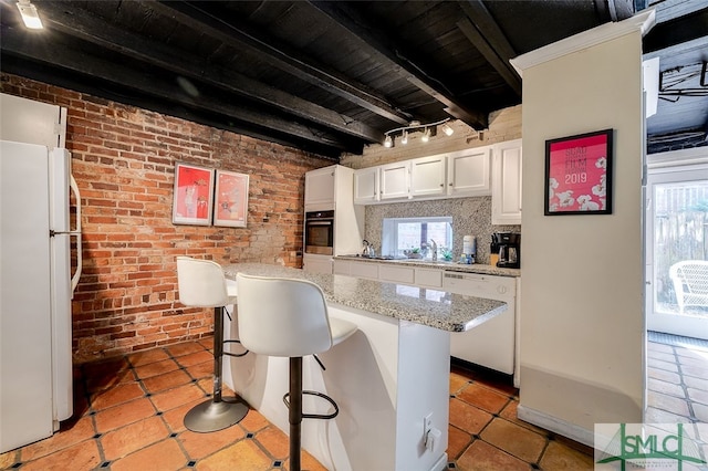 kitchen featuring a breakfast bar, white appliances, and a wealth of natural light