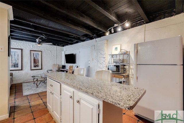 kitchen with wooden ceiling, white cabinets, light stone countertops, beam ceiling, and white fridge