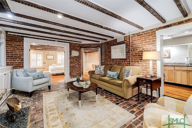 living room with beamed ceiling, dark hardwood / wood-style flooring, and brick wall