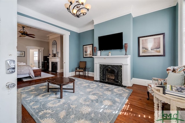 living room featuring dark hardwood / wood-style flooring, ceiling fan with notable chandelier, and ornamental molding