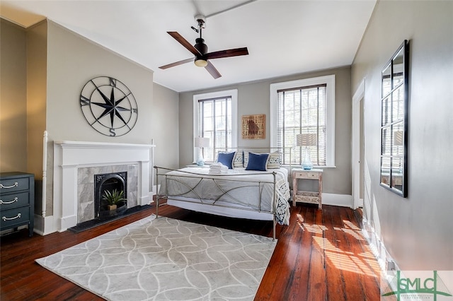 bedroom featuring ceiling fan, a fireplace, and dark wood-type flooring