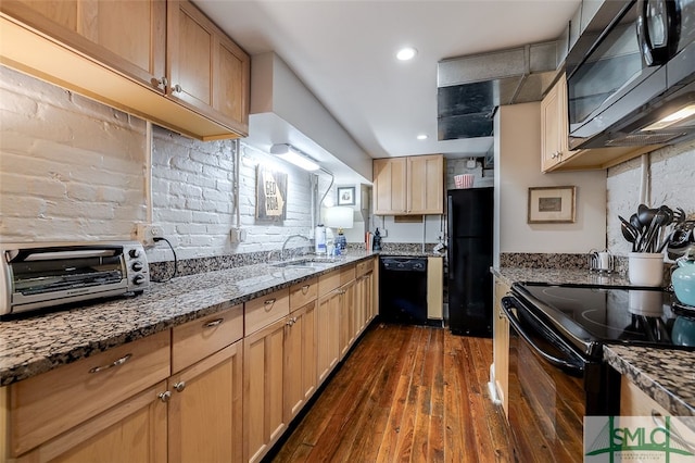 kitchen featuring dark wood-type flooring, stone counters, black appliances, sink, and light brown cabinetry