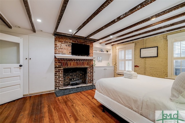 bedroom featuring a fireplace, wood-type flooring, and beamed ceiling