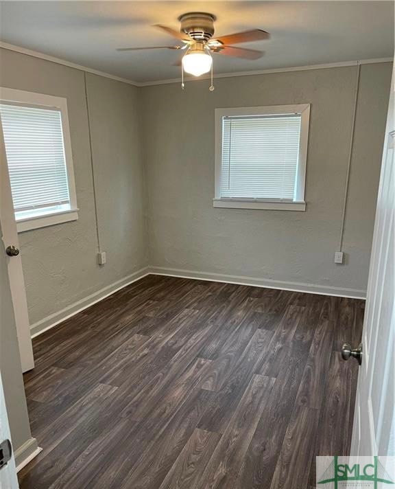 empty room featuring crown molding, dark wood-type flooring, and ceiling fan